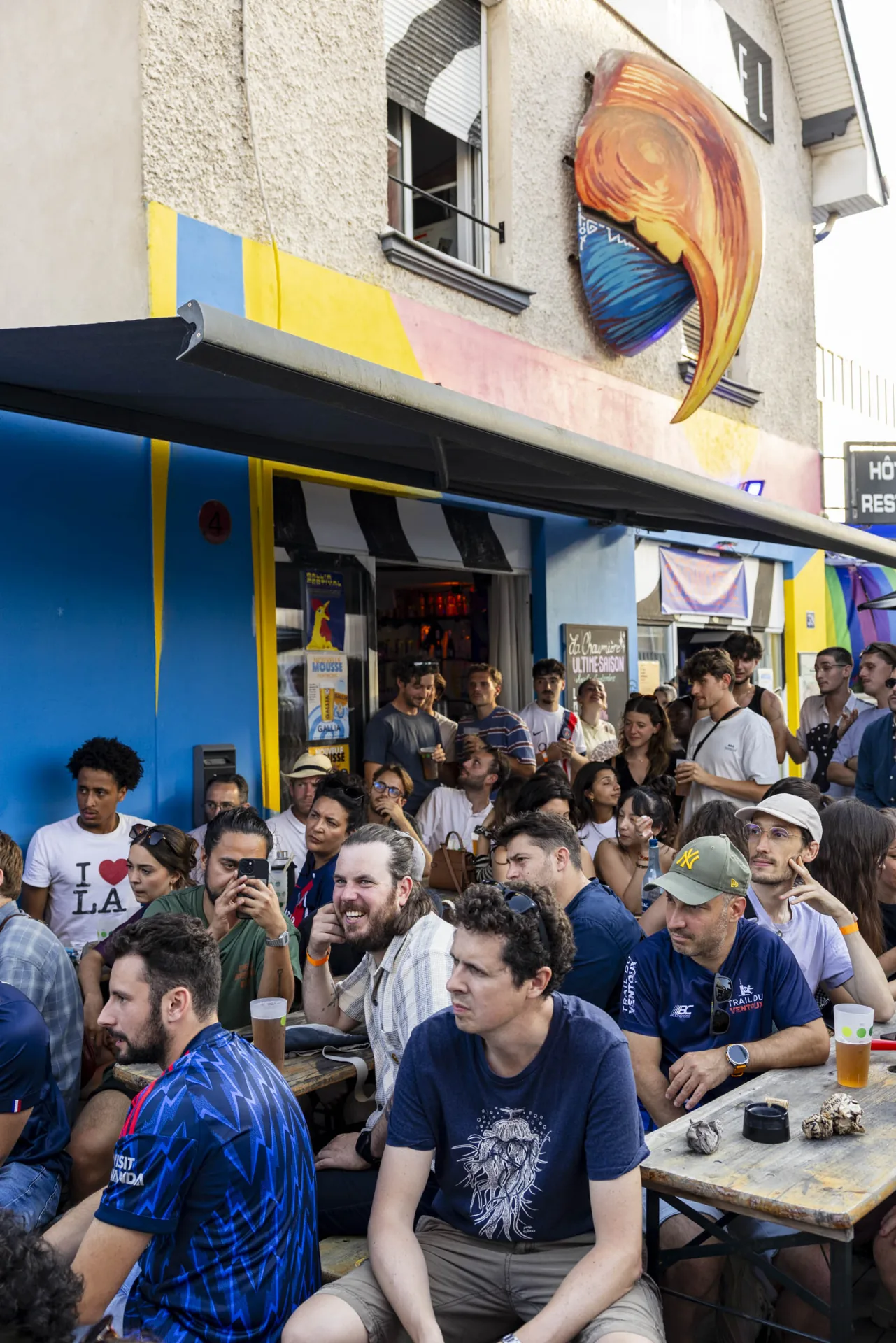 Terrasse comble devant la façade un après-midi de match — Bal Queer & Match Foot, 2026